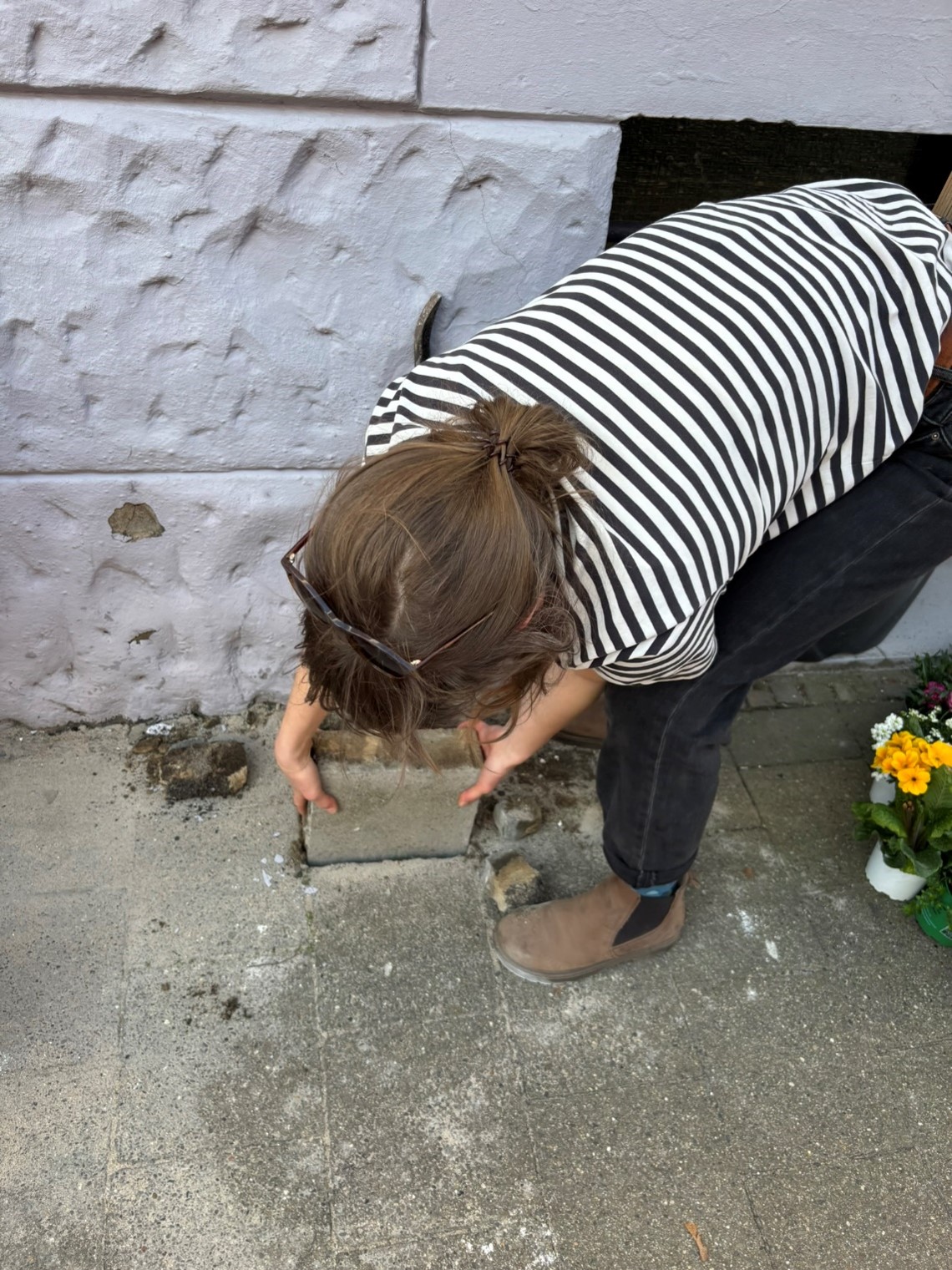 Person entfernt Pflastersteine, um Platz für Pflanzen zu schaffen, als Teil des Begrünungsprojekts Bodenluft.